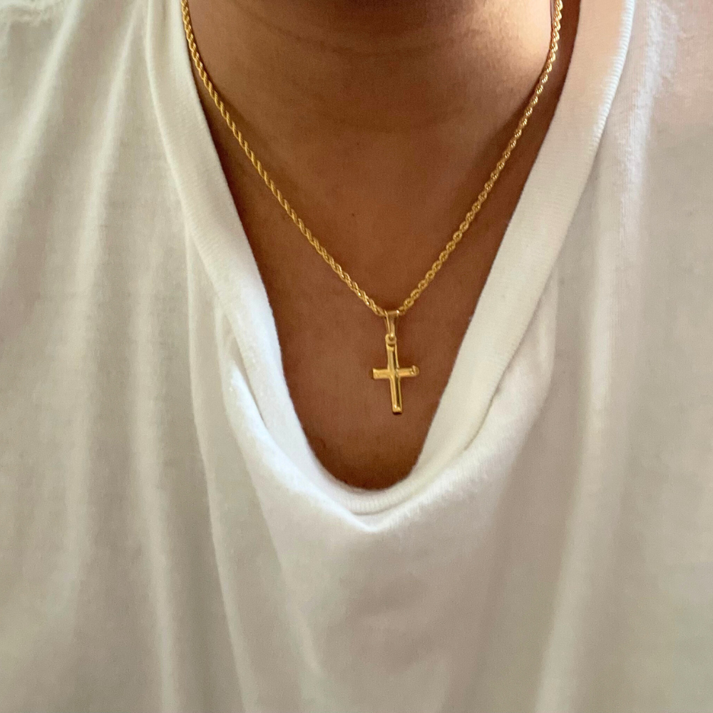 Gold-filled rope chain necklace with small cross pendant worn on a person’s neck, featuring a casual white shirt.