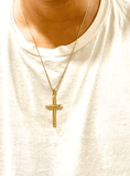 Load image into Gallery viewer, Gold cross pendant necklace worn on a person’s neck, featuring a delicate chain against a white t-shirt.
